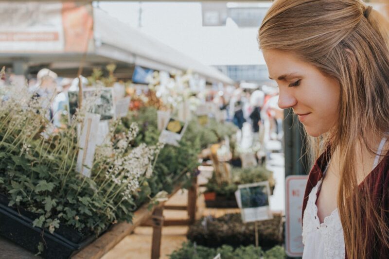Woman Looking at Plants in Garden