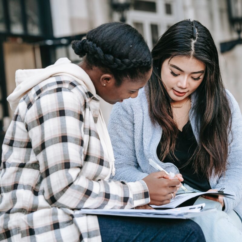Concentrated-female-students-fulfilling-task-in-campus-park