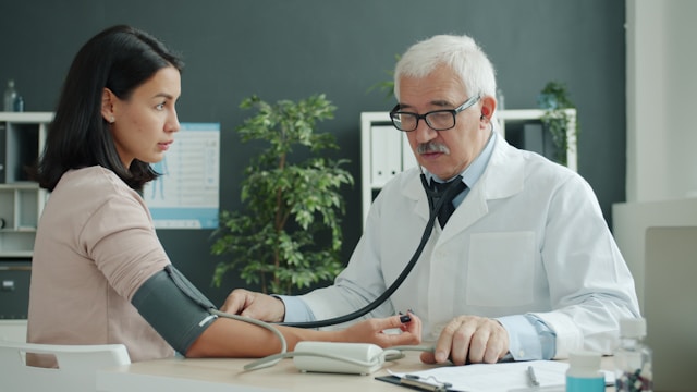 A doctor checking a patient’s blood pressure during a clinic visit, illustrating preventive care covered by the best health insurance plans for individuals.