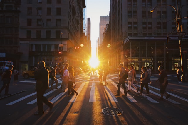 Pedestrians crossing a busy Manhattan street at sunset, representing the search for the best health insurance in New York.