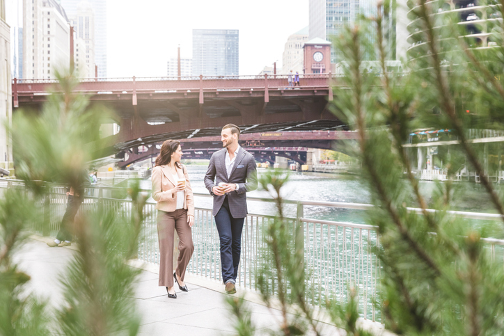 A man and woman walking along the Chicago Riverwalk, representing people researching the best health insurance in Illinois while enjoying the city’s downtown area.